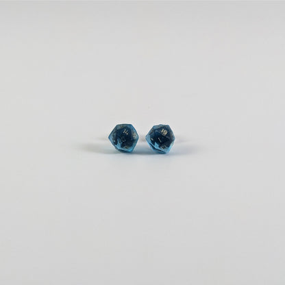 A single pair of the smaller size handmade d20 earrings with titanium hardware that are sapphire blue with bronze numbers on a white background. The earring on the left centers the 20 face and the earring on the right centers the 1 face.