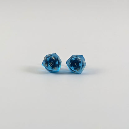 A single pair of the larger size handmade d20 earrings with titanium hardware that are sapphire blue with gold numbers on a white background. The earring on the left centers the 20 face and the earring on the right centers the 1 face.