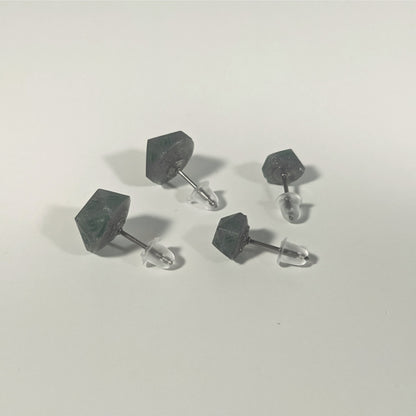 Two pairs of handmade d20 earrings that are dark silver with forest green numbers turned to show the titanium hardware and bell shaped rubber backs.