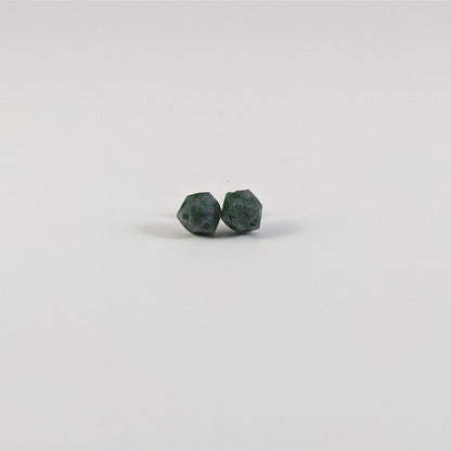 A single pair of the smaller size handmade d20 earrings with titanium hardware that are dark silver with forest green numbers on a white background. The earring on the left centers the 20 face and the earring on the right centers the 1 face.