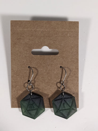 A pair of black and dark green dangly, flat d20 earrings with silver color titanium and niobium hardware on a kraft earring card on a white background. The earring on the left has a 20 on it and the earring on the right has a 1 on it, both in a fantasy style font.