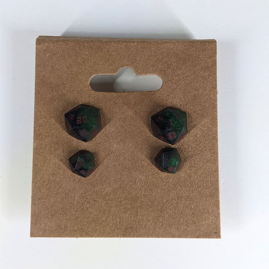 Two pairs of handmade d20 earrings that are dark green and black with red numbers on a kraft brown earring card. The earrings on the left of each pair centers the 20 face and the earrings on the right of each pair centers the 1 face.