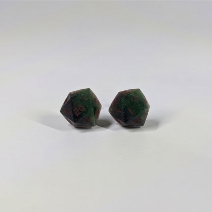 A single pair of the larger size handmade d20 earrings that are dark green and black with red numbers on a white background. The earring on the left centers the 20 face and the earring on the right centers the 1 face.