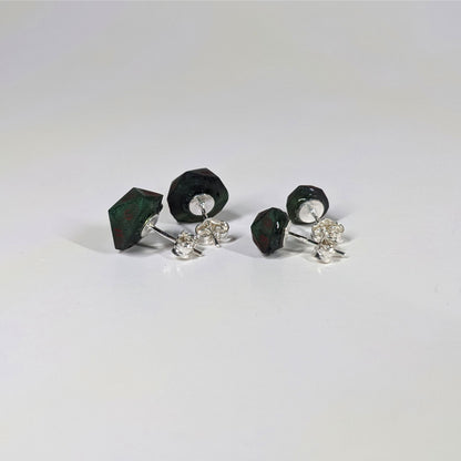 Two pairs of handmade d20 earrings that are dark green and black with red numbers turned to show the sterling silver hardware and butterfly backs.