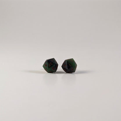 A single pair of the larger size handmade d20 earrings with sterling silver hardware that are dark green and black with red numbers on a white background. The earring on the left centers the 20 face and the earring on the right centers the 1 face.