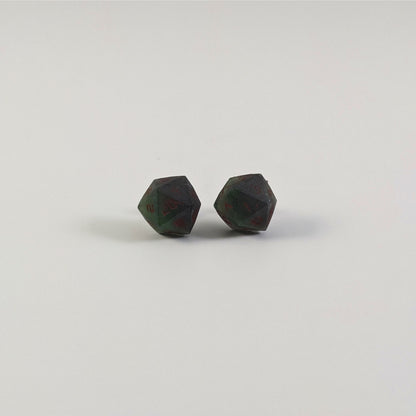 A single pair of the larger size handmade d20 earrings with titanium hardware that are dark green and black with deep red numbers on a white background. The earring on the left centers the 20 face and the earring on the right centers the 1 face.