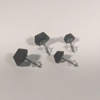 Two pairs of handmade d20 earrings that are dark green and black with deep red numbers turned to show the titanium hardware and bell shaped rubber backs.