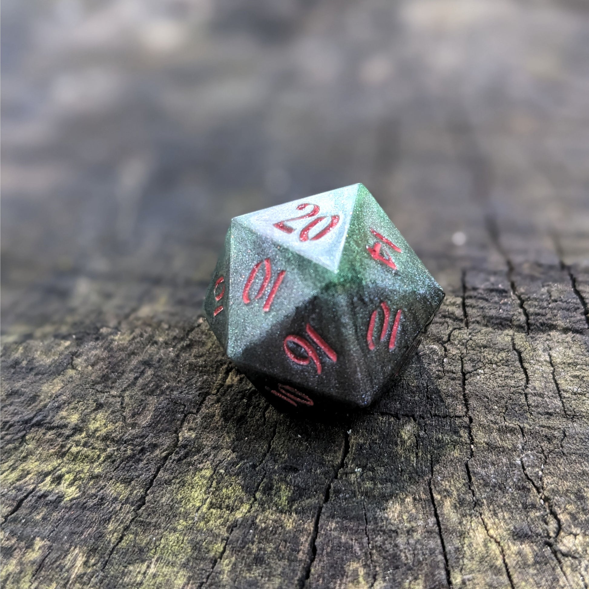 A close up photo of a dark green and black reliable talent d20 with red numbers sitting on a wood stump. Faces that would be 9 or below are replaced with a 10.