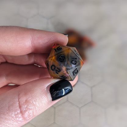 A d20 that is a glowy red-orange with a dark spherical insert and black numbers is held up to the camera to show off the red-orange swirls around the dark, spherical insert and otherwise clear shell. The 8 face is most angled toward the camera.