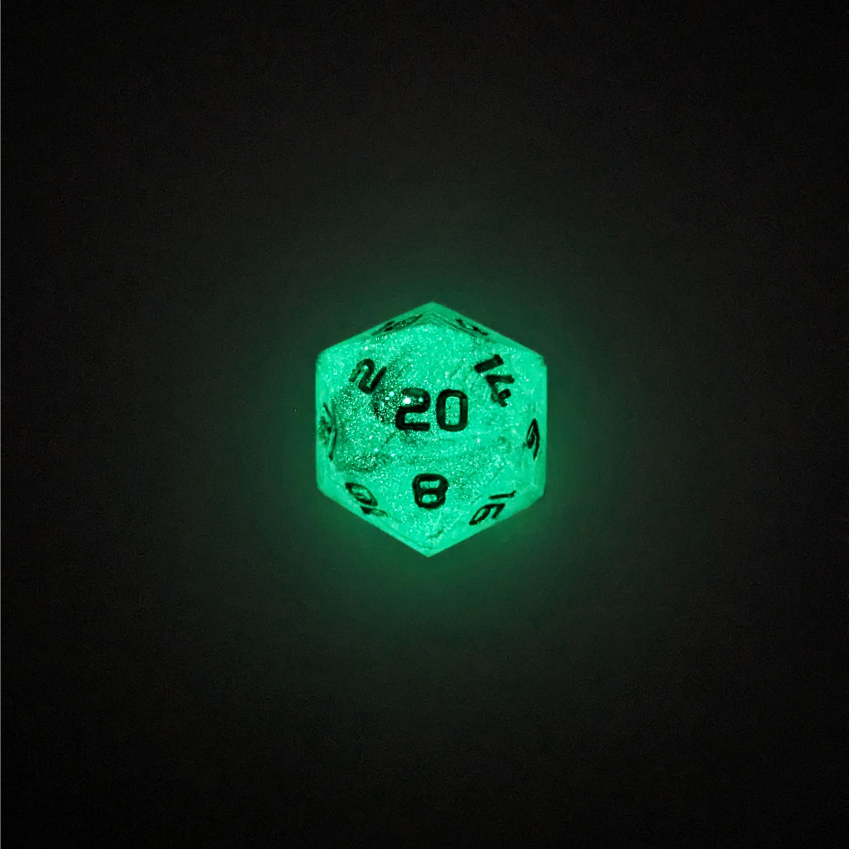 A high angle photo of a standard d20 glowing green with black swirls and green numbers with the 20 face up on a white background.