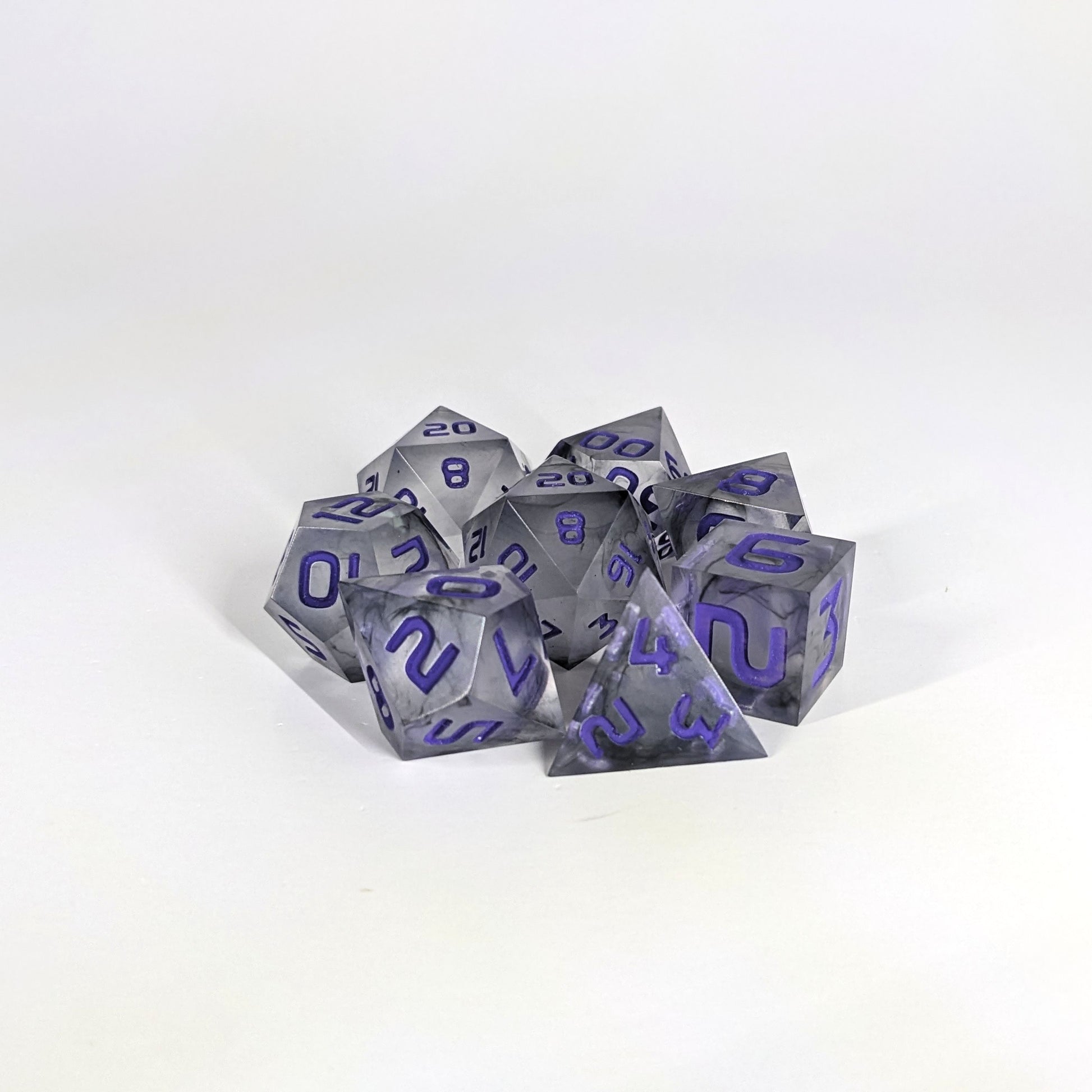A complete set of 8 handmade artisan dice that have black swirls around a cloudy spherical insert with purple numbers. The DnD dice set is arranged in a circle and features 2 D20s, one of which is in the center surrounded by the other 7 dice.