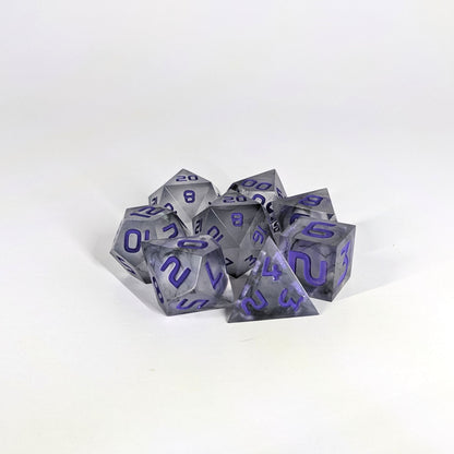 A complete set of 8 handmade artisan dice that have black swirls around a cloudy spherical insert with purple numbers. The DnD dice set is arranged in a circle and features 2 D20s, one of which is in the center surrounded by the other 7 dice.