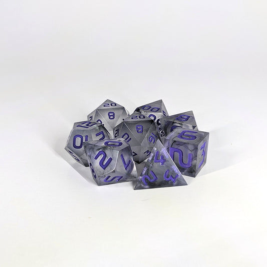 A complete set of 8 handmade artisan dice that have black swirls around a cloudy spherical insert with purple numbers. The DnD dice set is arranged in a circle and features 2 D20s, one of which is in the center surrounded by the other 7 dice.