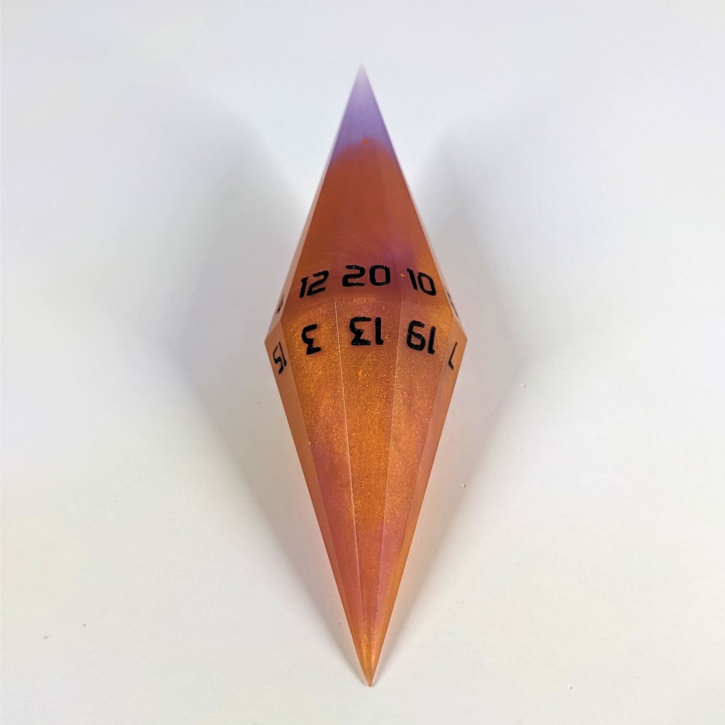 A mid angle shot of a purple and orange diamond d20 with black numbers on a white background.