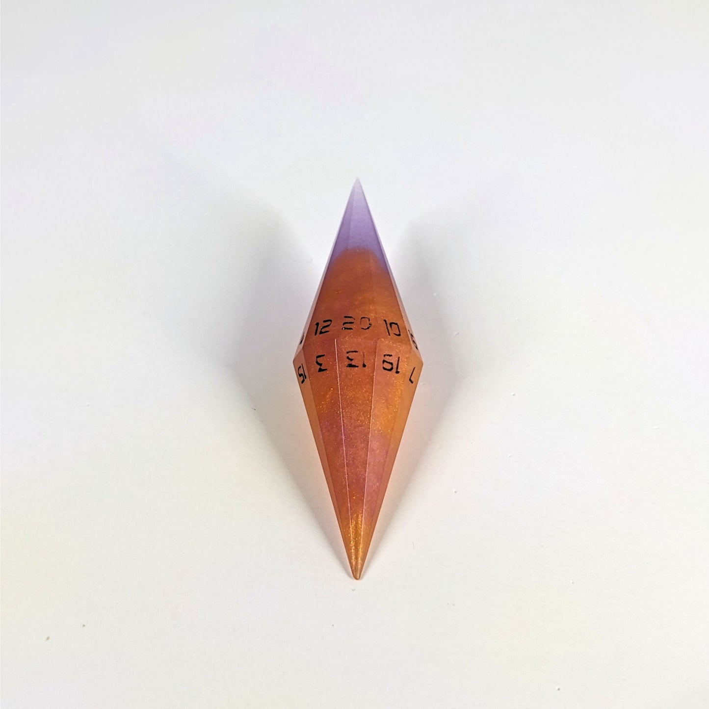 A high angle shot of a purple and orange diamond d20 with black numbers on a white background.