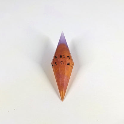 A high angle shot of a purple and orange diamond d20 with black numbers on a white background.