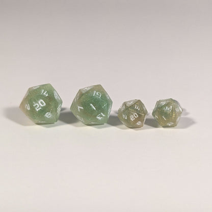 Two pairs of handmade d20 earrings with titanium hardware that are bright green and red gold with white numbers on a white background sit in a line with the larger pair on the left and the smaller pair on the right. The earrings on the left of each pair centers the 20 face and the earrings on the right of each pair centers the 1 face.