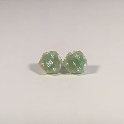 A single pair of the larger size handmade d20 earrings with titanium hardware that are bright green and red gold with white numbers on a white background. The earring on the left centers the 20 face and the earring on the right centers the 1 face.