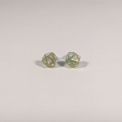A single pair of the smaller size handmade d20 earrings with titanium hardware that are bright green and red gold with white numbers on a white background. The earring on the left centers the 20 face and the earring on the right centers the 1 face.