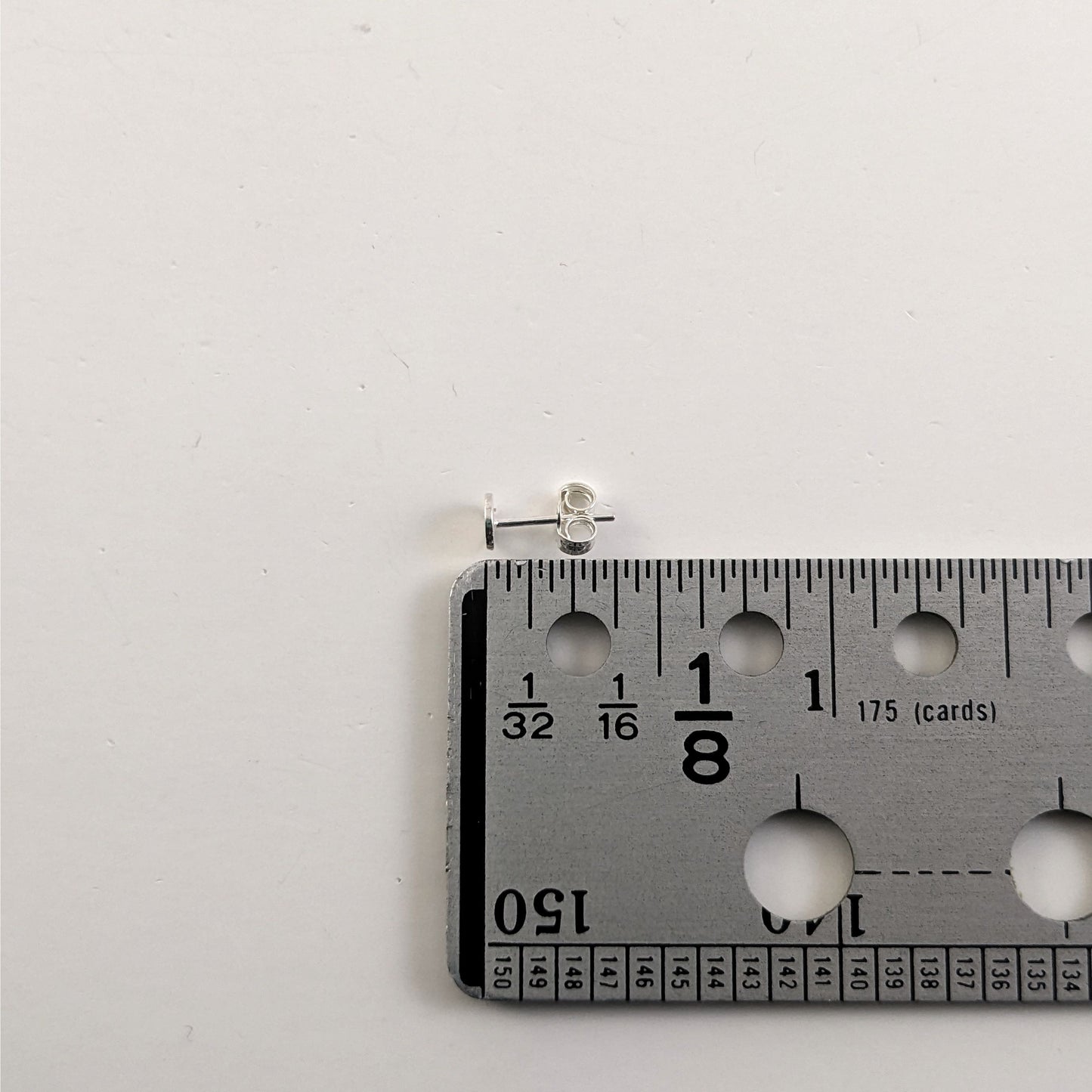 A size graphic of a sterling silver earring post and butterfly back next to a ruler and on a white background. It shows the length of the post as 9.5 mm or 0.37 in.
