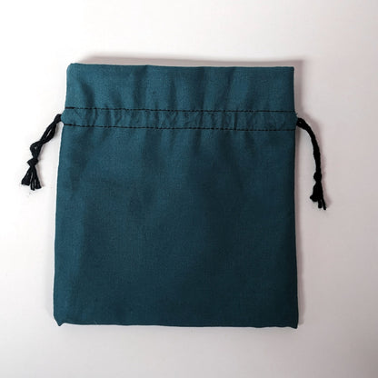 A teal, medium size dice bag lies flat and black drawstrings untightened on a white background.