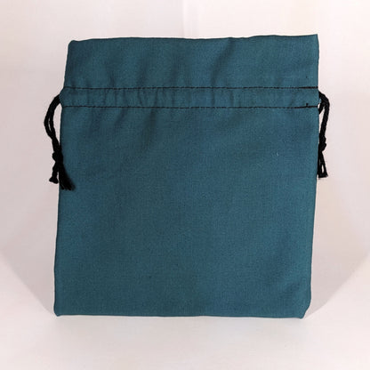 A teal, medium size dice bag that is sitting upright and not tied closed. The black drawstrings are visible on each side of the bag.