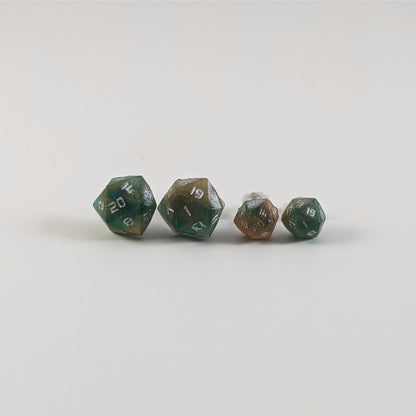 Two pairs of handmade d20 earrings with titanium hardware that are teal and copper swirls with silver numbers on a white background sit in a line with the larger pair on the left and the smaller pair on the right. The earrings on the left of each pair centers the 20 face and the earrings on the right of each pair centers the 1 face.