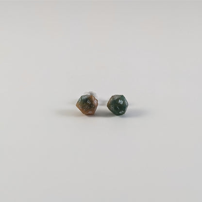 A single pair of the smaller size handmade d20 earrings with titanium hardware that are teal and copper swirls with silver numbers on a white background. The earring on the left centers the 20 face and the earring on the right centers the 1 face.