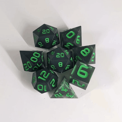 A gif showing a polyhedral dnd dice set in a circle with a d20 in the middle surrounded by the other 7 dice. The dice are black with some semitranslucent swirls and bright green numbers. The gif transitions from light to darkness and the dice shift from their normal color to glowing green in the dark.
