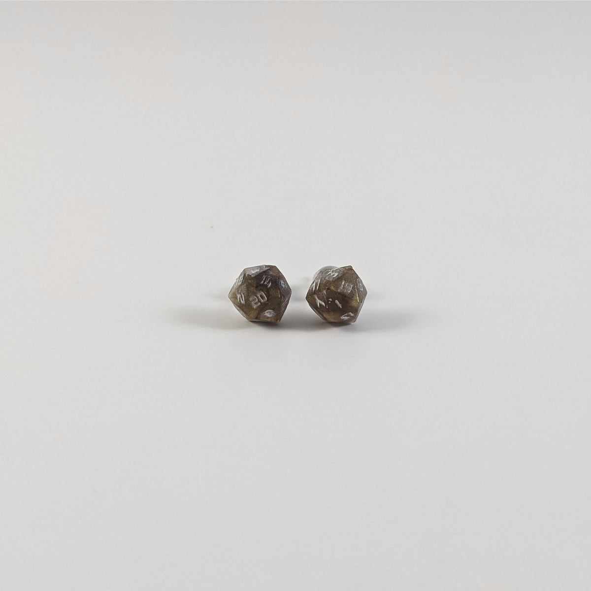 A single pair of the smaller size handmade d20 earrings with titanium hardware that are brown and yellow tiger's eye swirls with white numbers on a white background. The earring on the left centers the 20 face and the earring on the right centers the 1 face.