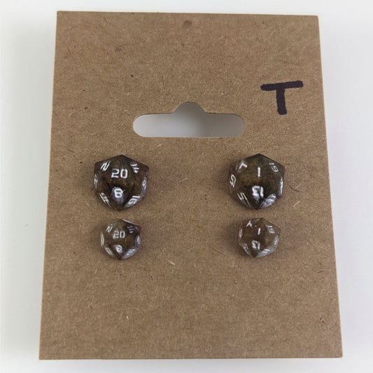 Two pairs of handmade d20 earrings with titanium hardware that are brown and yellow tiger's eye swirls with white numbers on a kraft brown earring card with a T in the top right corner. The earrings on the left of each pair centers the 20 face and the earrings on the right of each pair centers the 1 face.