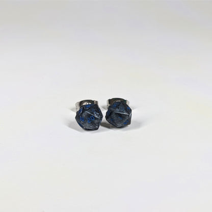 A single pair of the smaller size handmade d20 earrings that are black and dark silver with blue numbers on a white background. The earring on the left centers the 20 face and the earring on the right centers the 1 face.