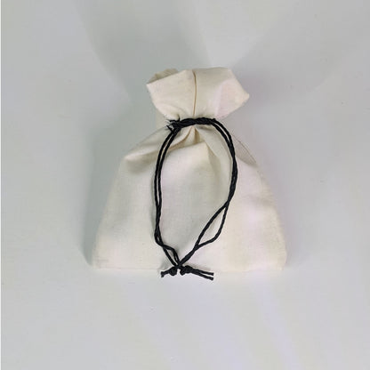 A small, handmade dice bag that is white is tied closed on a white background.