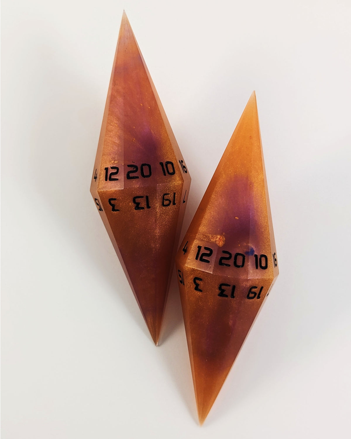 A high angle shot of two purple and orange diamond d20 with black numbers on a white background.