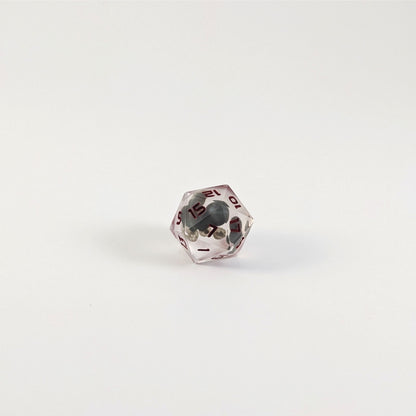 A close up of a d20 angled to show the main crater pattern of the moon design of the insert on a white background.