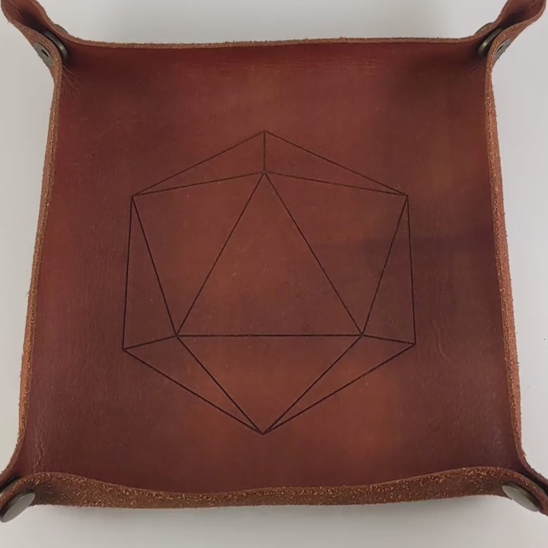 The video starts with a brown leather dice tray in view that has a d20 shape lasered into it. A hand appears from the bottom right corner holding a complete set of diamond dice that are mixed blue and semitransparent white with opaque white numbers. The hand rolls all of the dice into the tray from the right.