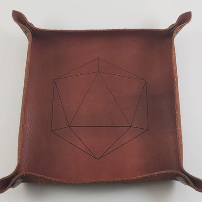 The video starts with a brown leather dice tray in view that has a d20 shape lasered into it. A hand appears from the bottom right corner holding a pair of yellow and teal d12s, one with white numbers and one with black numbers. The hand rolls the dice into the dice tray from the right.