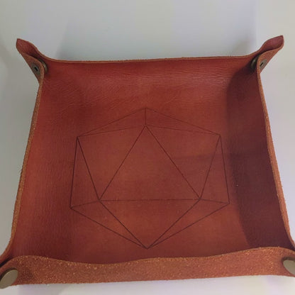 The video starts with a brown leather dice tray in view that has a d20 shape lasered into it. A hand appears from the bottom right corner holding a complete set of polyhedral dice that are clear with red, spherical inserts and black numbers. The hand rolls all of the dice into the tray from the right.