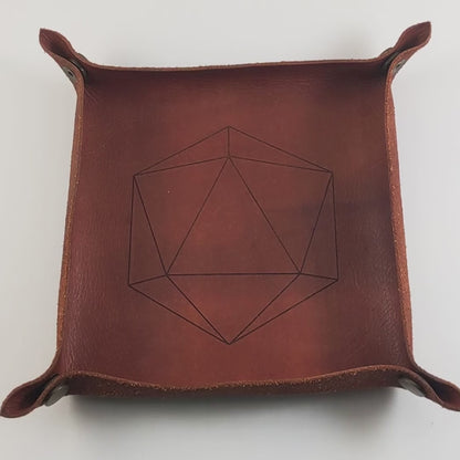 The video starts with a brown leather dice tray in view that has a d20 shape lasered into it. A hand appears from the bottom right corner holding a complete set of polyhedral dice that have swirls of translucent pink, purple, green, blue, and white with opaque white numbers. The hand rolls all of the dice into the tray from the right.