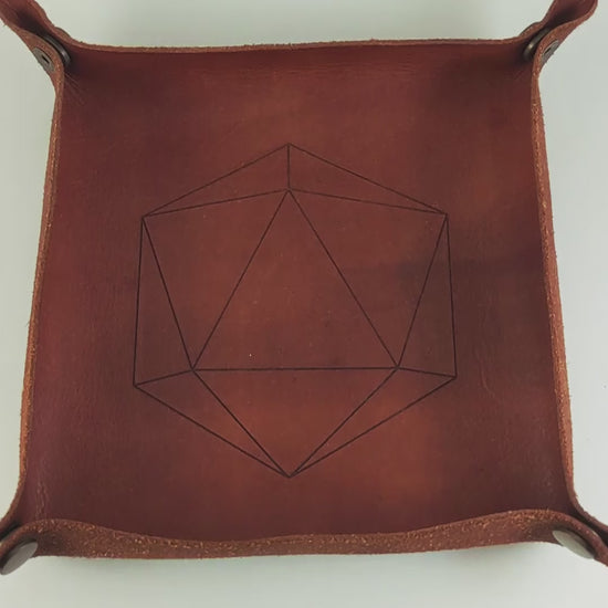 The video starts with a brown leather dice tray in view that has a d20 shape lasered into it. A hand appears from the right side holding a complete set of diamond dice that are swirling shades of green with black numbers. The hand rolls all of the dice into the tray from the right.