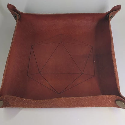 The video starts with a brown leather dice tray in view that has a d20 shape lasered into it. A hand appears from the bottom right corner holding a complete set of polyhedral dice that are black with some semitranslucent swirls and bright green numbers. The hand rolls all of the dice into the tray from the right.