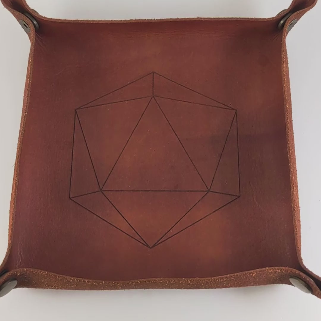 The video starts with a brown leather dice tray in view that has a d20 shape lasered into it. A hand appears from the bottom right corner holding a complete set of diamond dice that are swirls of electric blue with grey numbers. The hand rolls all of the dice into the tray from the right.