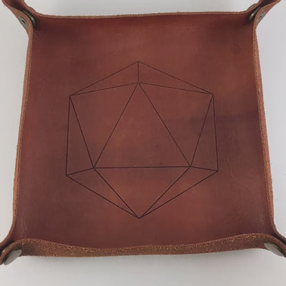 The video starts with a brown leather dice tray in view that has a d20 shape lasered into it. A hand appears from the bottom right corner holding a complete set of diamond dice that are yellow and teal swirls with white numbers. The hand rolls all of the dice into the tray from the right.