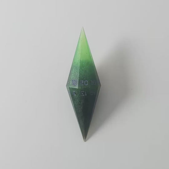 A video of a diamond d20 with swirls of black and green with purple numbers that glow in the dark on a white background. This transitions from light to darkness to show the purple numbers glowing green in the dark.