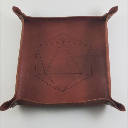 The video starts with a brown leather dice tray in view that has a d20 shape lasered into it. A hand appears from the bottom right corner holding a complete set of teal polyhedral dice with a pearlescent shine and copper numbers. The hand rolls all of the dice into the tray from the right.