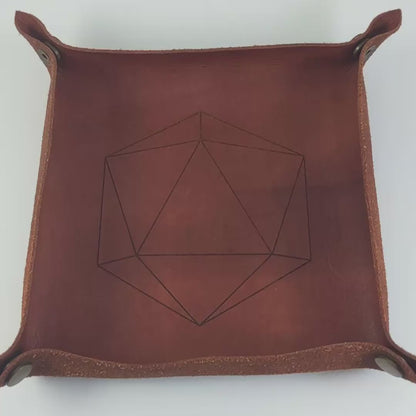 The video starts with a brown leather dice tray in view that has a d20 shape lasered into it. A hand appears from the bottom right corner holding a complete set of polyhedral dice that are clear with a hand painted green glow in the dark ooze design and silver numbers. The hand rolls all of the dice into the tray from the right. One of the d20s lands on a natural 20.