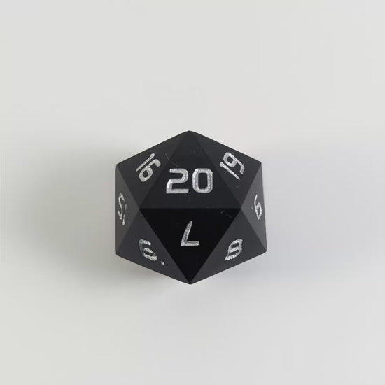 A black spindown d20 with silver numbers counts down from 20 to 1 in a stop motion video showing the spindown pattern of the right spindown die.