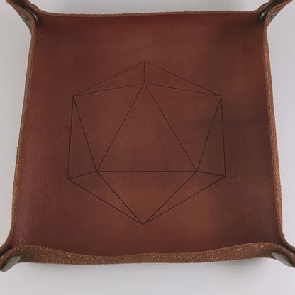 The video starts with a brown leather dice tray in view that has a d20 shape lasered into it. A hand appears from the bottom right corner holding a complete set of dagger dice that are frosty blue and white with a touch of sparkle with opaque white numbers. The hand rolls all of the dice into the tray from the right.