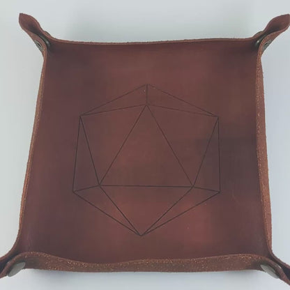 The video starts with a brown leather dice tray in view that has a d20 shape lasered into it. A hand appears from the bottom right corner holding an orange and purple dagger d20 with black numbers. The hand rolls all of the dice into the tray from the right. The die rolls an 18.