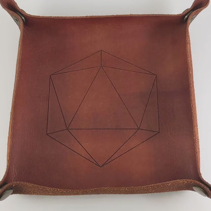 The video starts with a brown leather dice tray in view that has a d20 shape lasered into it. A hand appears from the bottom right corner holding a complete set of diamond dice that are deep maroon and dark silver with white numbers. The hand rolls all of the dice into the tray from the right.